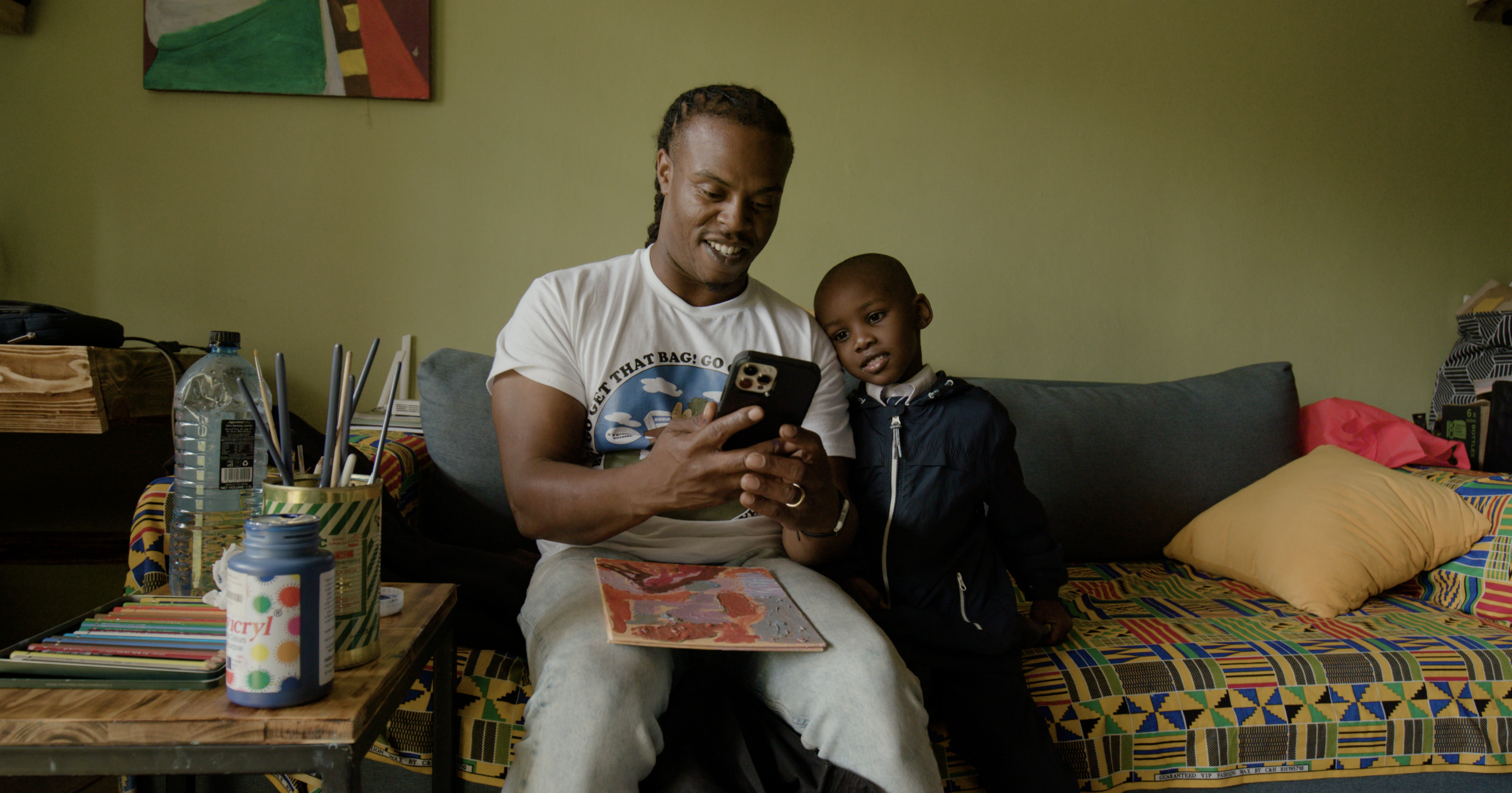 Man with a phone in his hand shows new technology to a kid sitting by his side
